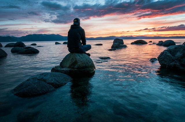 Watching sunset on rock in water
