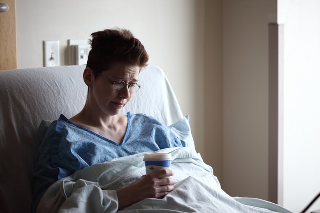 Sick worker in bed holding cup
